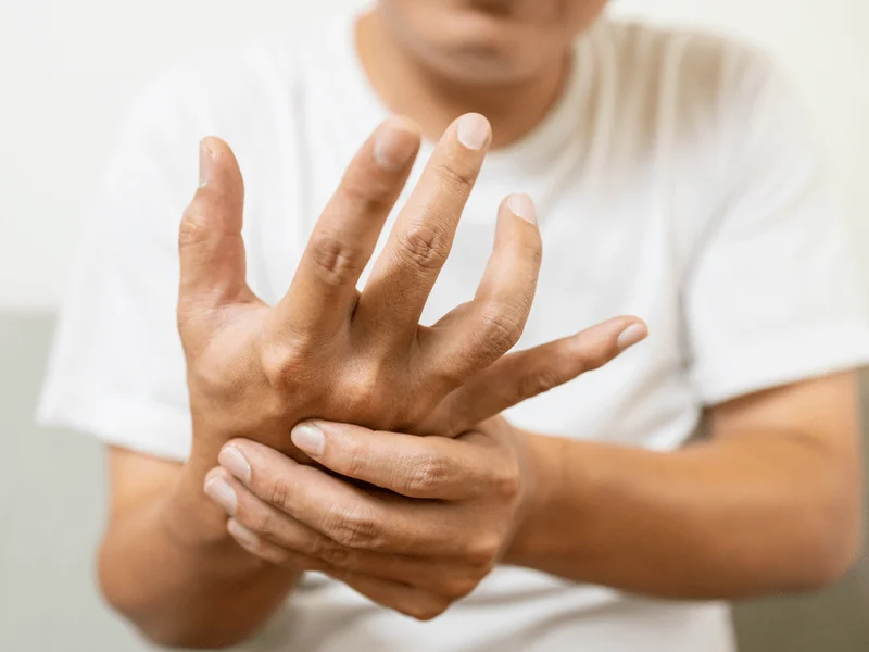 Person holding their own hand, showing hand tremor