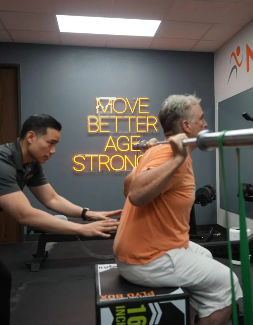 Doctor of Physical Therapy guiding a patient through a supervised barbell squat at Next Level PT in Kingwood