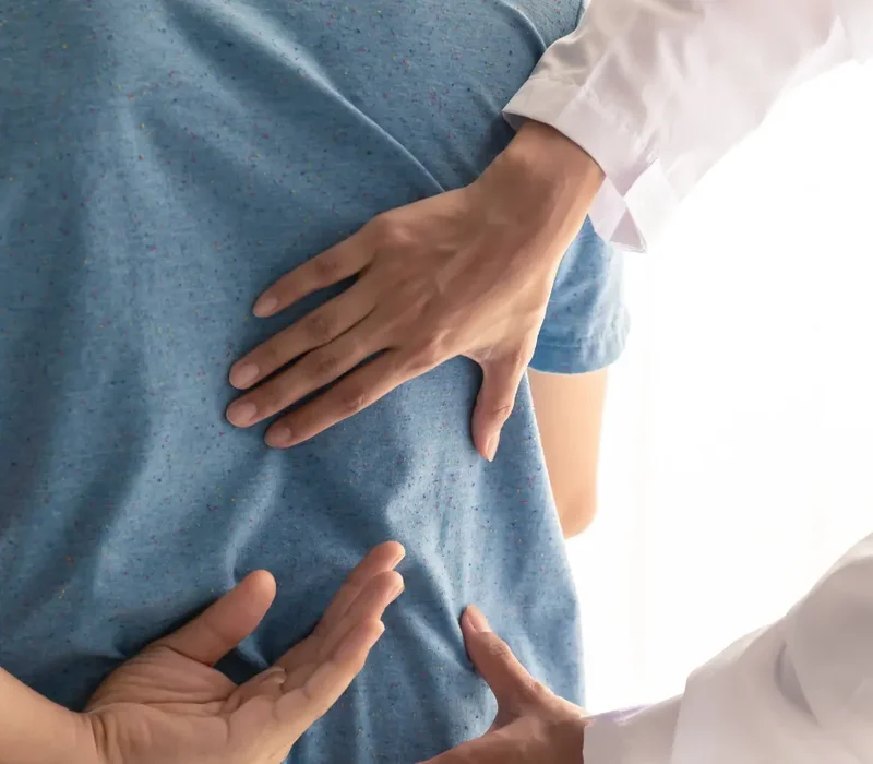 Clinician palpating a patient's back during an exam