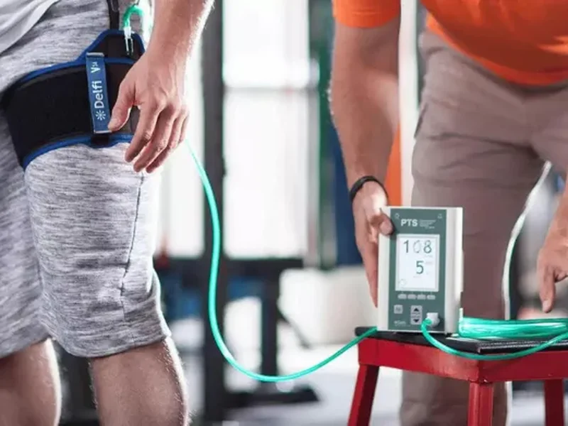 Doctor of Physical Therapy applying a blood flow restriction cuff during a light-load training session