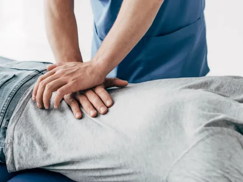 Doctor of Physical Therapy performing hands-on joint mobilization on a patient's lower back