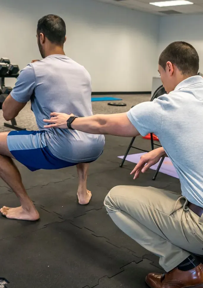 Dr. Jack Wong guiding a patient through a squat at Next Level Regenerative Physical Therapy